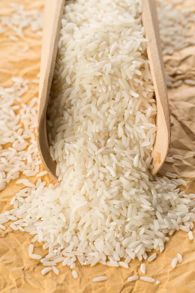 Heap of white uncooked, raw long grain rice in wooden scoop — Stock Photo, Image