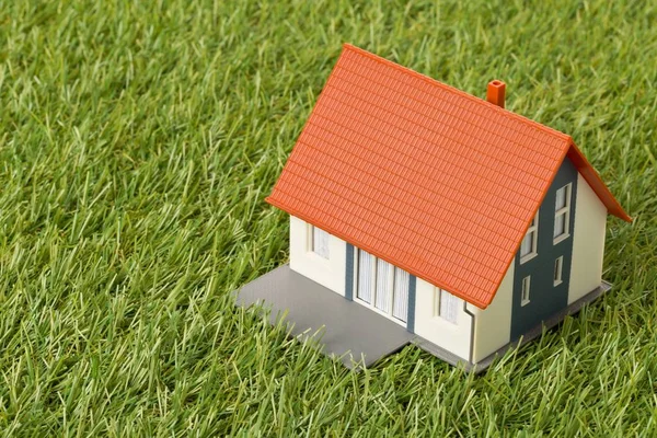 Miniatuur huis model op groen gras gazon achtergrond — Stockfoto