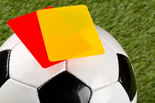 Primer plano del árbitro tarjetas amarillas y rojas en la parte superior de la pelota de fútbol — Foto de Stock