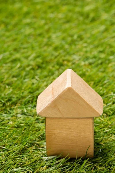 Klein houten miniatuur huis model op groen gras achtergrond — Stockfoto