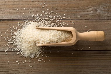 Beyaz pişmemiş, çiğ uzun tahıllı pirinç, ahşap kepçe.