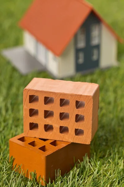 Miniature bricks with house model on green grass lawn background — Stock Photo, Image