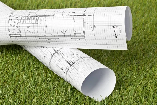 Архитектурные чертежи на зеленом фоне газона — стоковое фото