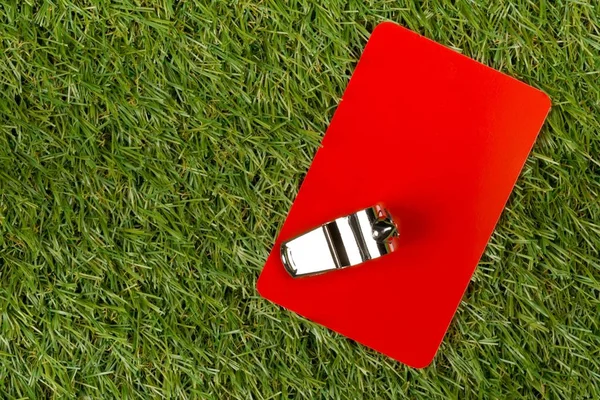 Soccer sports referee red card with chrome whistle on grass background