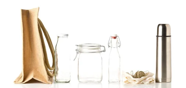 Zero waste or waste free shopping utensils with burlap bag, glass bottles and cotton bag over white background