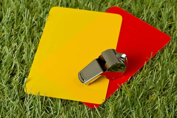 Árbitro deportivo de fútbol tarjetas amarillas y rojas con silbato de cromo en el fondo de hierba - pena, falta o concepto de deportes —  Fotos de Stock