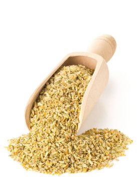 Bir yığın pişmemiş, çiğ freekeh veya firik, kavrulmuş buğday, beyaz üzerine ahşap kepçe