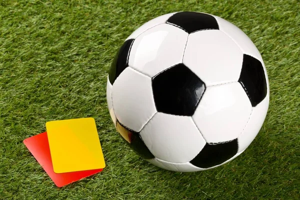 Balón de fútbol con árbitro tarjetas amarillas y rojas en el fondo de hierba - pena, falta o concepto de deportes — Foto de Stock