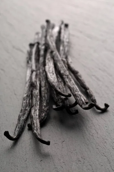 Pacchetto di fave di vaniglia o baccelli di bourbon essiccati su tavola di pietra nera — Foto Stock
