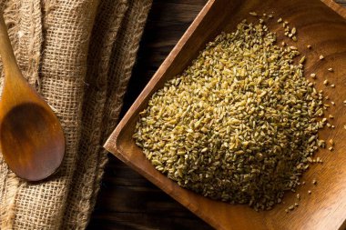Pişmemiş, çiğ freekeh veya firik, kavrulmuş buğday taneciği, ahşap tabakta, kahverengi masa arkası manzarası düz, yukarıdan bakıldığında düz.