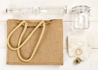 Çuval bezi, cam şişeler ve pamuk torbalı sıfır atık veya atıksız alışveriş gereçleri yukarıdaki beyaz ahşap masa arka planında yer almaktadır - atık azaltma eko yaşam tarzı veya toptan market konsepti satın alma