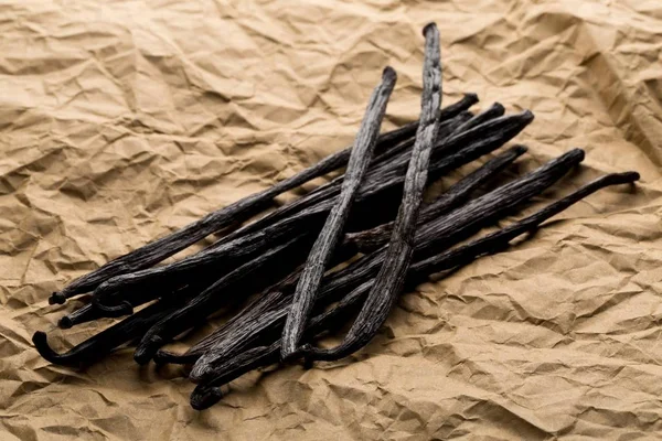 Bundle of dried bourbon vanilla beans or pods on brown packing paper flat lay top view from above