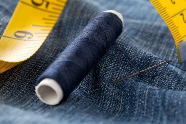 Mavi iplikli iğne iplik ve kot pantolona ölçü bandı yakın - kot pantolon moda onarım veya onarım konsepti, seçici odaklanma