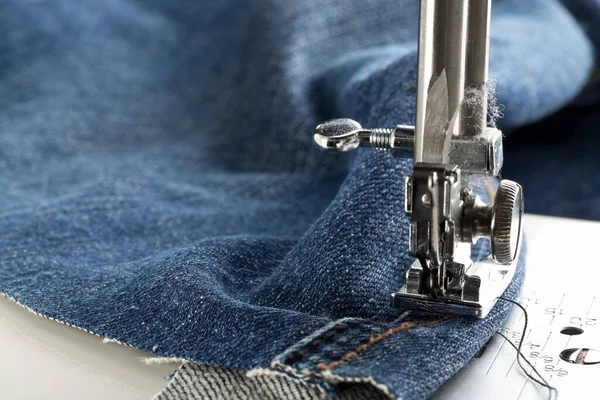 ミシンの近くに縫い付けられたブルージーンズデニム ジーンズのファッションの修正や修理の概念 選択的な焦点 — ストック写真