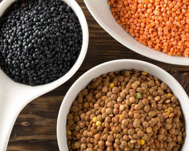 Farklı çeşitteki mercimekler, beyaz kâselerdeki kırmızı, kahverengi ve siyah beyaz beyaz mercimeklerle karıştırılır.