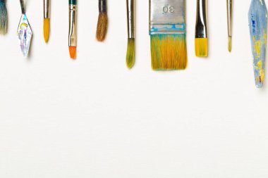 Beyaz arkaplanda boya fırçaları ve fotokopi alanı düz manzaralı sanat malzemeleri yukarıdan görünüm verdi