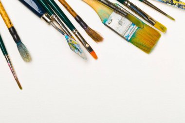 Beyaz arkaplanda boya fırçaları ve fotokopi alanı düz manzaralı sanat malzemeleri yukarıdan görünüm verdi
