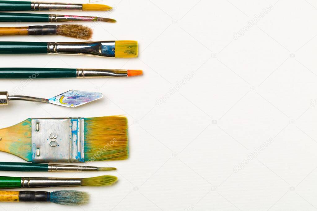 Artistic art supply utensils with paintbrushes on white background with copy space flat lay top view from above