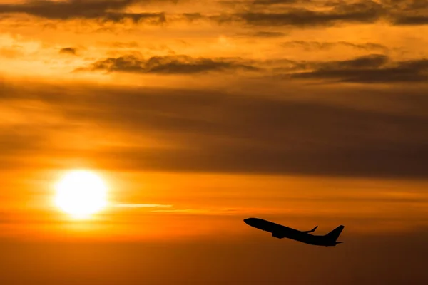 Um avião voando em direção a um belo pôr do sol — Fotografia de Stock
