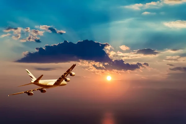 Um avião voando em direção a um belo pôr do sol — Fotografia de Stock