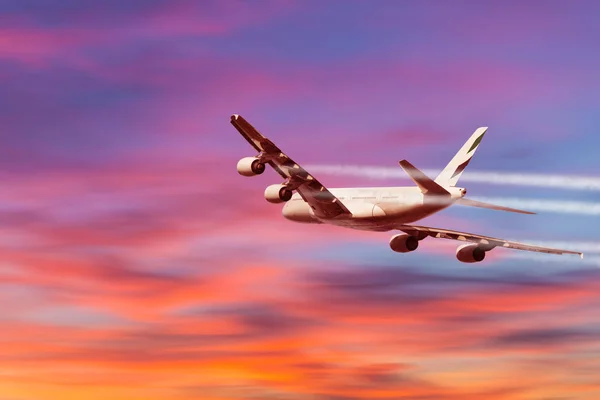 Um avião voando em direção a um belo pôr do sol — Fotografia de Stock