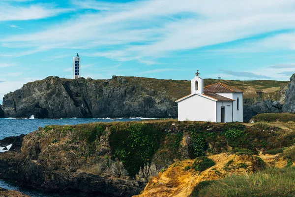 Chiesa sulla scogliera rocciosa in riva al mare con faro sullo sfondo — Foto Stock