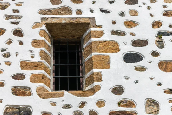 Okno z kratami na białej ścianie z kamieniami — Zdjęcie stockowe