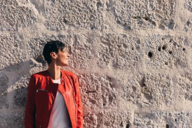 Genç kadın kısa siyah saçlı kırmızı ceketli taş duvar