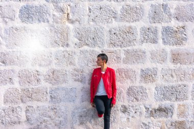 Genç kadın kısa siyah saçlı kırmızı ceketli taş duvar
