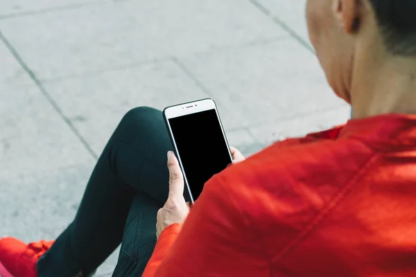 Kadın elleri kırmızı ceketli, akıllı telefon kullanıyor.