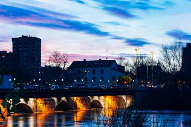 Geceleri nehrin üzerindeki taş köprüyü aydınlatıyordu.