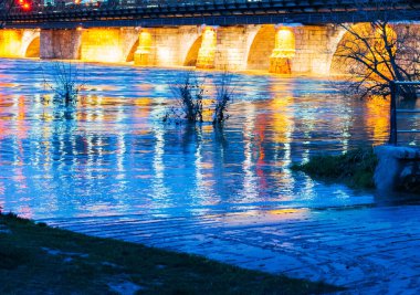 Geceleri nehrin üzerindeki taş köprüyü aydınlatıyordu.