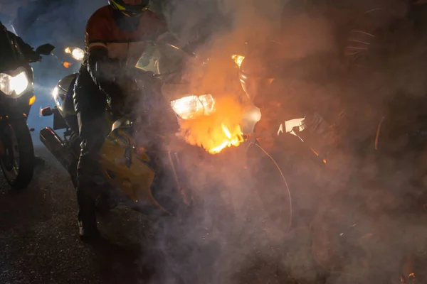 Night motorcycle parade with torches in the fog