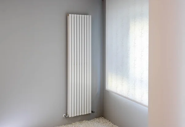 White radiator on gray wall with window — Stock Photo, Image