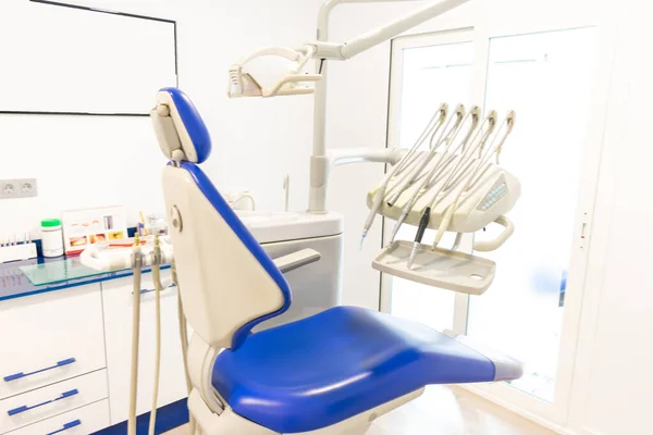 Diş kliniğinde beyaz duvarlı mavi bir dişçi koltuğu.