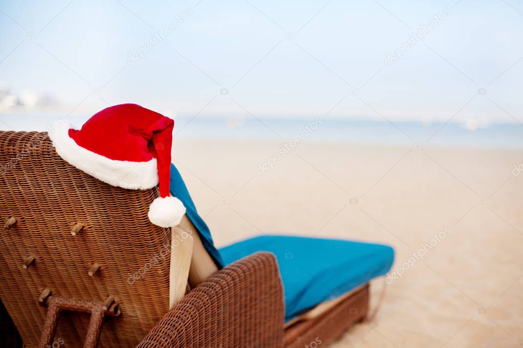 Beach chair with santa hats on the beach with sea view. Christmas and New Year holidays in the concept of warm countries.