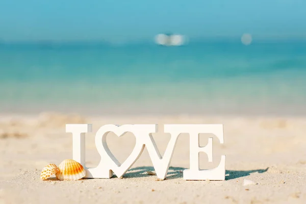 Wooden letters love on a sandy beach overlooking the blue sea