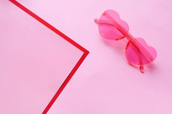 Rosa Sonnenbrille in Herzform auf zartem rosa Hintergrund mit roten Streifen in Form einer Ecke und einem Platz für Text. modischer und kreativer Hintergrund — Stockfoto