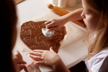 Mutfaktaki çocuklar kalp şeklindeki hamurdan ev yapımı kurabiyeler yapıyorlar. Yakın çekim, üst görünüm