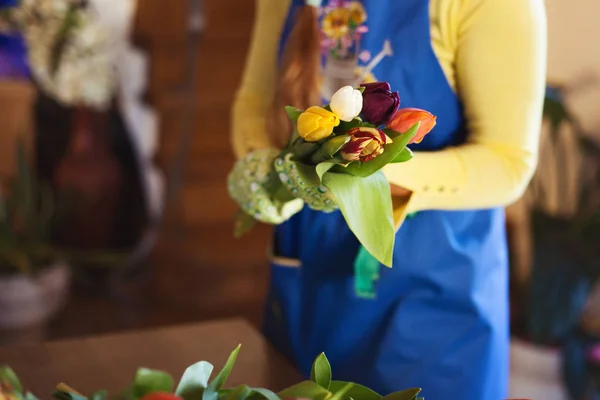 Çiçekçi kız kraft kağıdındaki bir çiçekçide güzel laleler paketliyor. Kadınlar Günü ve Sevgililer Günü — Stok fotoğraf