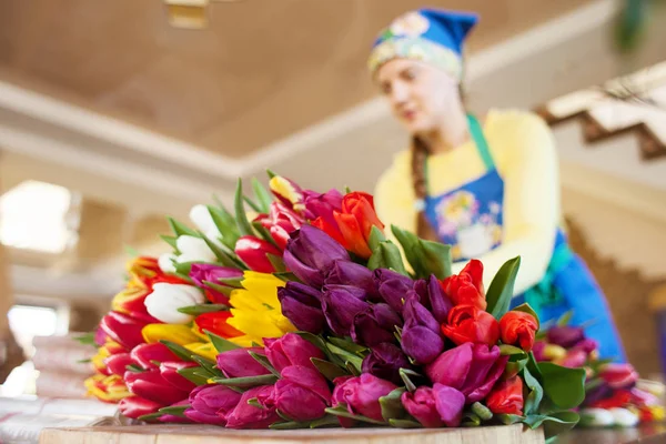 Girl florist is packing beautiful tulips in a flower shop in kraft paper. Women\'s Day and Valentine\'s Day