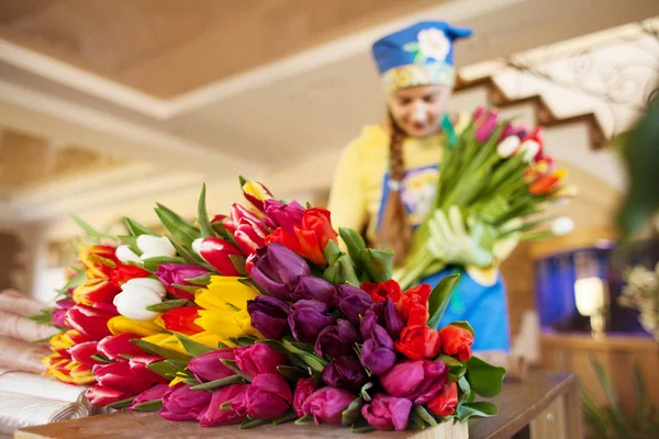 女花匠正在用牛皮纸把漂亮的郁金香装在花店里。 儿童节及情人节 — 图库照片