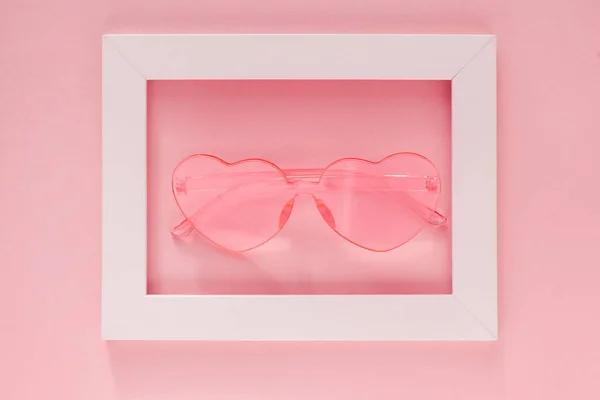 Розовые очки в форме сердца в белой рамке на розовом фоне. Открытка, подарок, поздравление с Днем Святого Валентина и женским днем. Вид сверху — стоковое фото