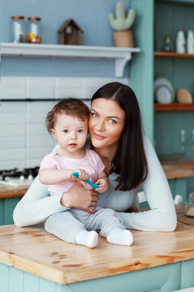 Glada barn sitter i köket vid bordet med mamma håller en sked i handen — Stockfoto