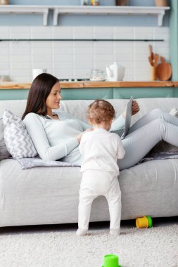 Annesi, çocuğu oyun oynarken evde bir dizüstü bilgisayarda çalışıyor. İş ve aile kavramı.