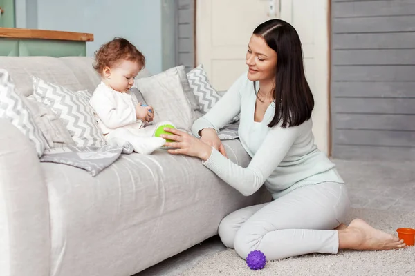 Liten bebis och mamma leker i rummet på soffan med ljusa gummibollar. — Stockfoto