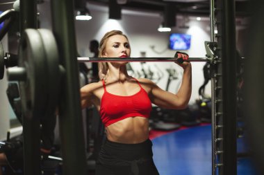 Güzel genç atletik kadın spor salonunda antrenman yapıyor. Spor kıyafetli bir kız halterle egzersiz yapıyor. Spor, spor, spor, stil, yaşam tarzı