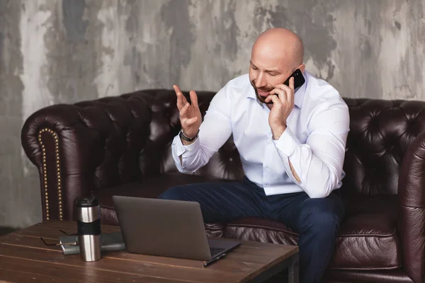 Confident adult man talks on the phone sitting at the computer. Business portrait, business, work