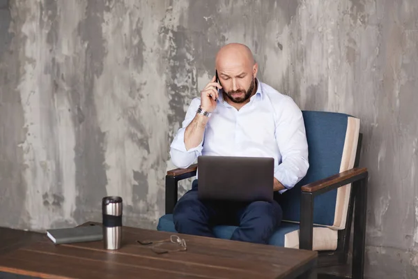 Confident adult man talks on the phone sitting at the computer. Business portrait, business, work