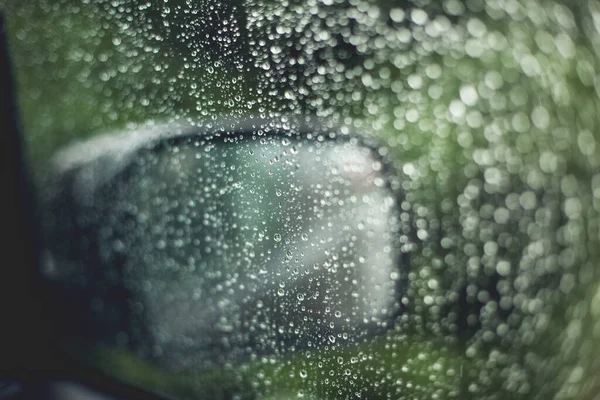 Raindrops on the car\'s glass window. Raindrops on the transparent window, on the glass. Weather, rain, texture. Blurred background